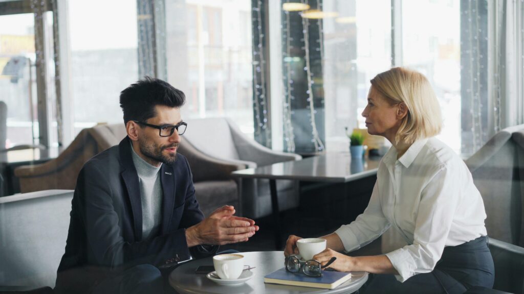 A business professional speaking with a prospective customer during a strategy-focused meeting.